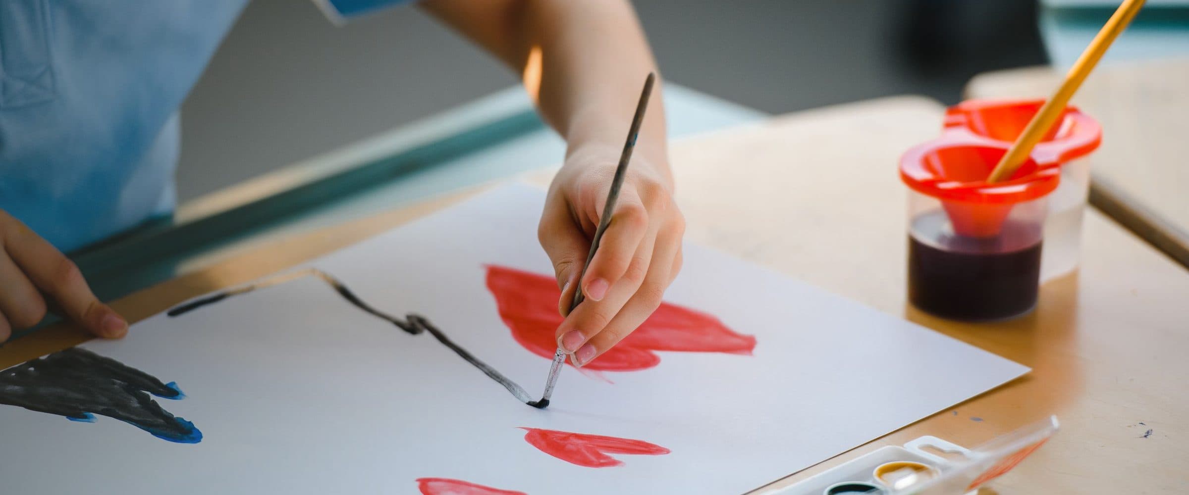 Enfant peignant à la gouache sur une grande feuille